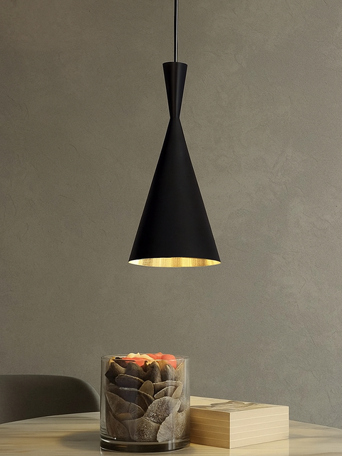 Modern black cone pendant light hanging above a minimalist table with decorative stones and a book, ideal for contemporary interior lighting design.