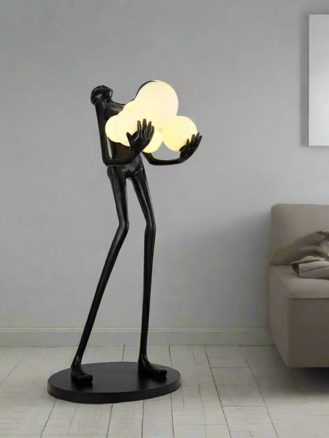 Modern black sculptural floor lamp holding glowing cloud-shaped lights – luxury artistic lighting for contemporary home interiors by Tatva Lights.