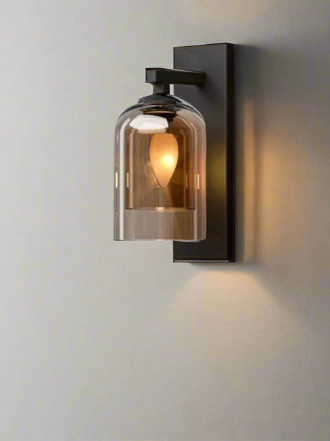 Modern black and glass wall sconce with dome-shaped shade and warm LED bulb mounted on a textured bedroom wall – ideal for ambient indoor lighting