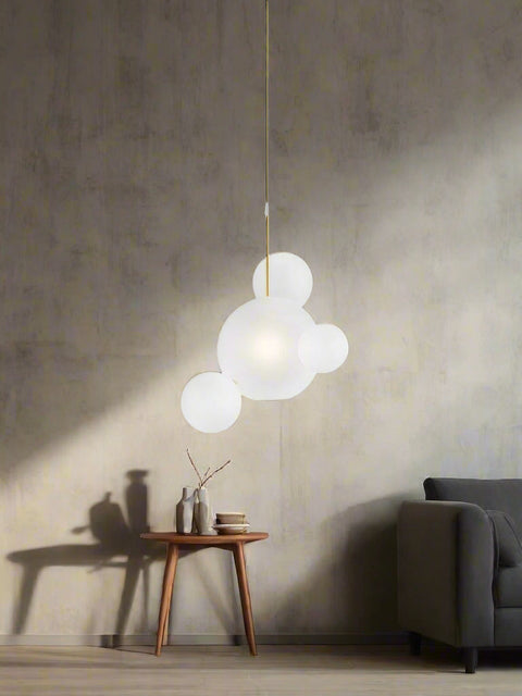 Tatva Lights modern cluster pendant light with frosted glass globe design, suspended over a contemporary dining table setup with muted green and dark panel walls, creating a soft and elegant ambient glow.