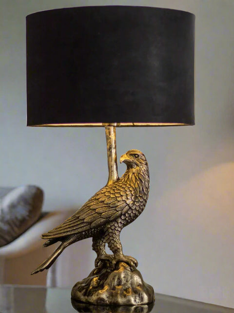 Tatva Lights AUREL Table Lamp featuring a majestic eagle-shaped metallic base with a textured antique finish, topped with a bold black cylindrical lampshade—perfect for adding a regal and artistic touch to any modern or classic interior décor.