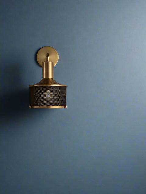 Tatva Lights AMBER GLOW Wall Sconce โ a modern industrial wall light with a sleek gold-finished metal arm and black perforated mesh shade, radiating warm ambient lighting. Ideal for contemporary living rooms, hallways, bedrooms, or feature walls, offering a perfect blend of style and sophistication.