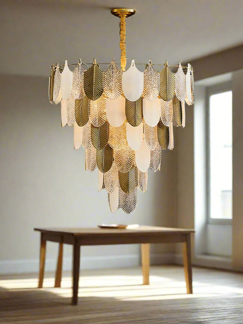 A contemporary silver chandelier with a geometric frost pattern and gold accents, hanging over a dark wood and marble coffee table in a living room setting.