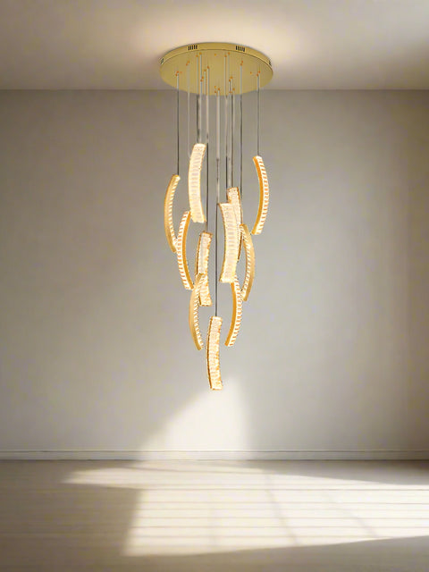 An elegant chandelier with double height and crystal stairwell design, hanging in a sophisticated interior with light gold walls and elegant furnishings.