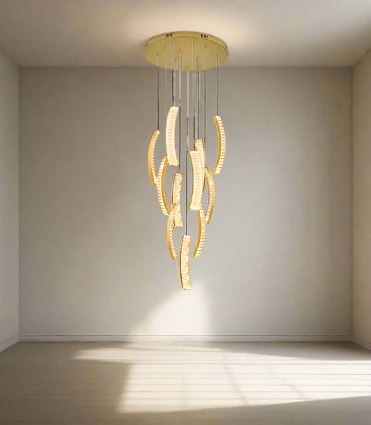 An elegant chandelier with double height and crystal stairwell design, hanging in a sophisticated interior with light gold walls and elegant furnishings.