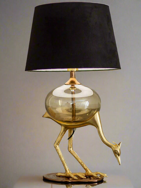 Tatva Lights Flamingo Metal Glass Table Lamp featuring a sculpted golden flamingo base, round glass body, and elegant black lampshade—perfect for adding a bold, artistic touch to luxury modern interiors.