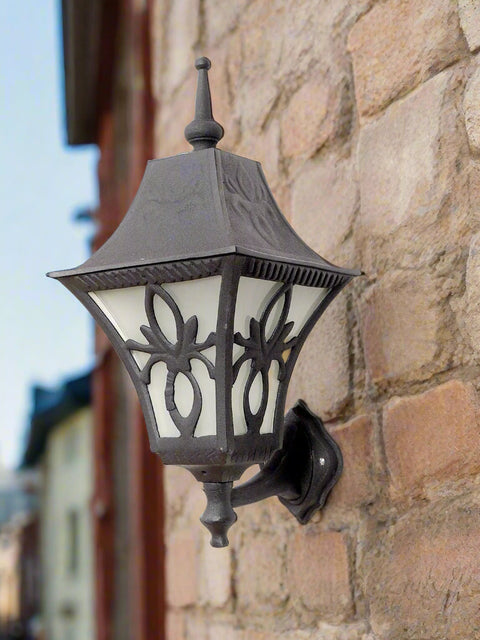 Tatva Lights FleurGlow outdoor wall lantern in a vintage black finish, featuring ornate floral-inspired ironwork and frosted panels for ambient exterior lighting on porches, patios, or garden walls.