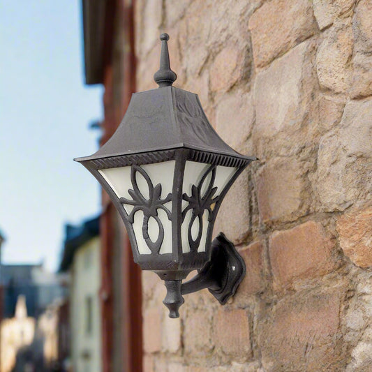 Tatva Lights FleurGlow outdoor wall lantern in a vintage black finish, featuring ornate floral-inspired ironwork and frosted panels for ambient exterior lighting on porches, patios, or garden walls.