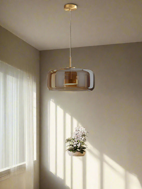 Tatva Lights Honeyloop Hanging Light – a stylish amber glass pendant with a smooth dome shape and gold detailing, crafted to enhance modern dining spaces with warm, ambient lighting