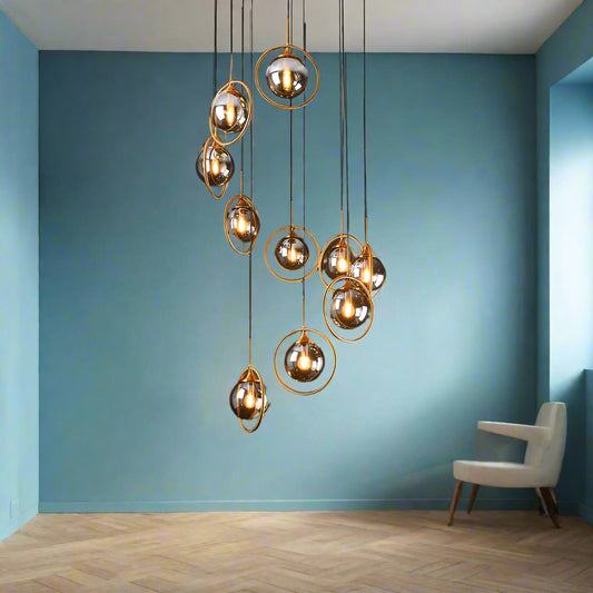 A luxurious chandelier by Tatva Lights, the "Opaline Reign" features 10 elegant lights suspended at varying heights, perfect for double-height ceilings and staircases. With a golden metallic structure and opal-glass globes, it offers a royal, ambient glow using energy-efficient LED lighting.