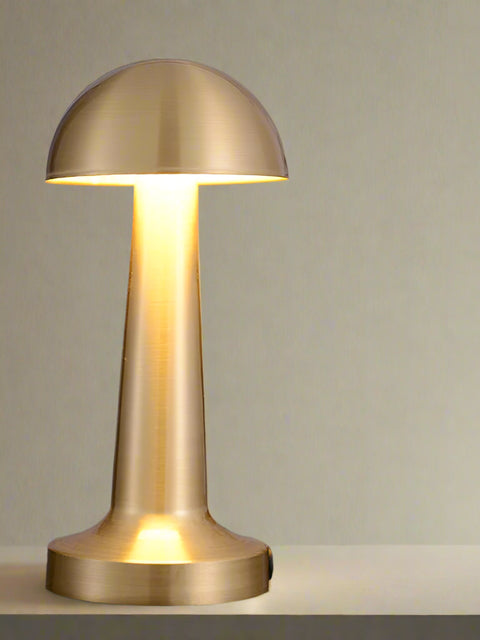 Tatva Lights brushed gold mushroom-style LED table lamp with a sleek dome-shaped head and cylindrical base, placed on a dark marble surface. Ideal for modern dining tables, sideboards, or ambient accent lighting in contemporary interiors