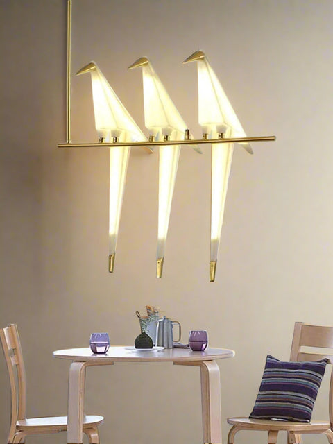 Tatva Lights Tri-Canary LED Hanging Light featuring three bird-shaped acrylic diffusers perched on a sleek gold-finished horizontal rod, combining playful design with warm ambient lighting — ideal for modern dining or living spaces.