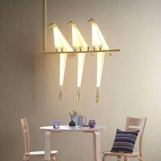 Tatva Lights Tri-Canary LED Hanging Light featuring three bird-shaped acrylic diffusers perched on a sleek gold-finished horizontal rod, combining playful design with warm ambient lighting — ideal for modern dining or living spaces.