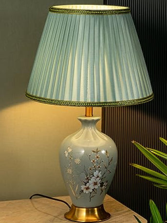 A green striped ceramic table lamp with a floral pattern on the base, featuring a gold-colored metal base and a matching gold-colored lampshade.