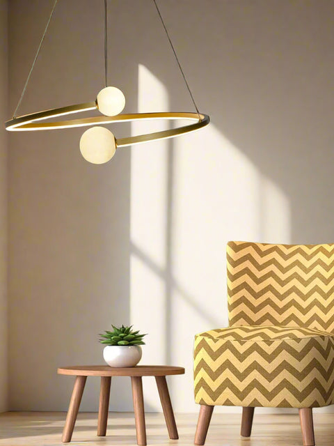 Tatva Lights “Vita” Gold Metal & Glass Hanging Light with dual opal glass globes suspended in a modern ring design.
Perfect for contemporary living rooms, dining areas, or high ceilings seeking artistic lighting.
Crafted with a matte gold finish and ambient LED glow for a luxurious, sculptural statement.