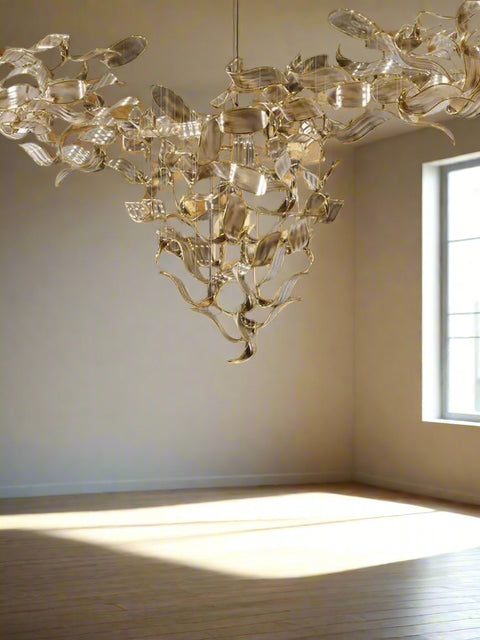 Tatva Lights Wove Custom Glass Chandelier โ handcrafted designer chandelier with interwoven glass design and premium metallic finish. Ideal for modern living rooms, dining areas, and luxury interiors. Adds ambient lighting and elegant dรฉcor appeal to any space.