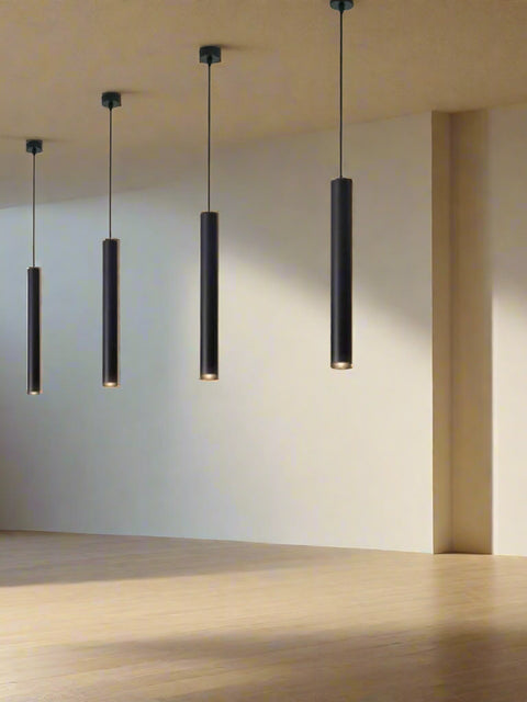 Tatva Lights Modern LED pendant lights with a cylindrical shape, hanging in a row over a kitchen counter with a white brick wall in the background.