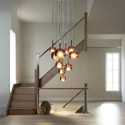 A modern stairwell featuring the Tatva Lights Amber Glow Cluster Chandelier with warm amber glass domes, perfect for luxury interiors and contemporary stairway lighting décor.