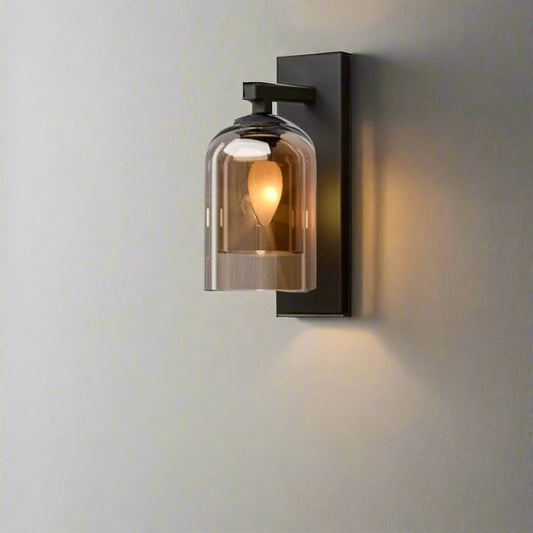 Modern black and glass wall sconce with dome-shaped shade and warm LED bulb mounted on a textured bedroom wall – ideal for ambient indoor lighting