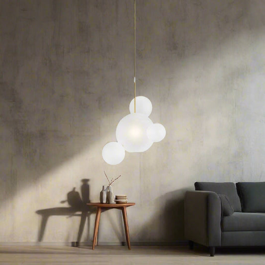 Tatva Lights modern cluster pendant light with frosted glass globe design, suspended over a contemporary dining table setup with muted green and dark panel walls, creating a soft and elegant ambient glow.
