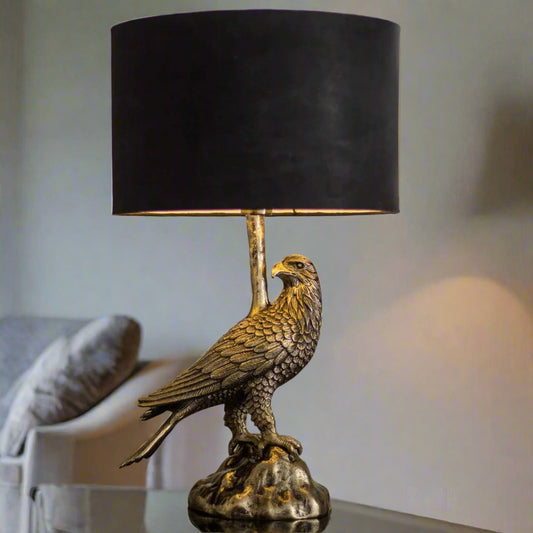 Tatva Lights AUREL Table Lamp featuring a majestic eagle-shaped metallic base with a textured antique finish, topped with a bold black cylindrical lampshade—perfect for adding a regal and artistic touch to any modern or classic interior décor.