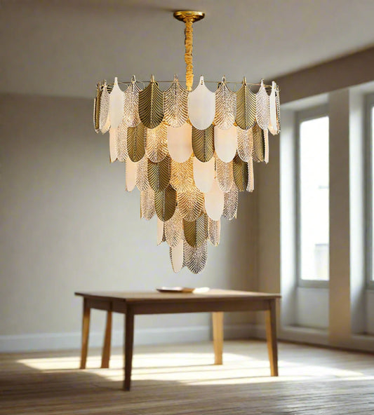 A contemporary silver chandelier with a geometric frost pattern and gold accents, hanging over a dark wood and marble coffee table in a living room setting.