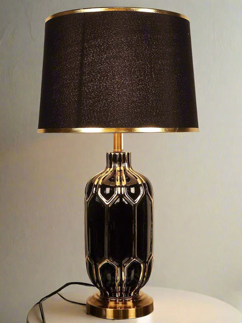 Tatva Lights Gold-Embroidered Ceramic Table Lamp featuring a glossy black ceramic base with intricate gold detailing, paired with a matching black lampshade trimmed in gold—an opulent lighting piece that brings sophistication and drama to any space.