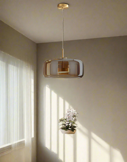 Tatva Lights Honeyloop Hanging Light – a stylish amber glass pendant with a smooth dome shape and gold detailing, crafted to enhance modern dining spaces with warm, ambient lighting