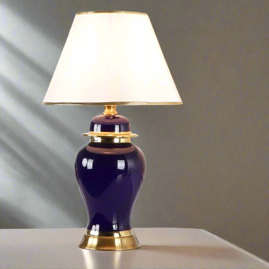 Tatva Lights Multi Color Ceramic Table Lamp featuring a rich deep blue ceramic base with elegant gold accents, paired with a classic white lampshade trimmed in gold—perfect for adding a touch of sophistication and color contrast to any décor.