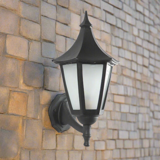 Elegant black outdoor wall lantern with frosted glass panels and vintage design, mounted on a textured white wall — perfect for balconies, patios, and garden entrances by Tatva Lights.