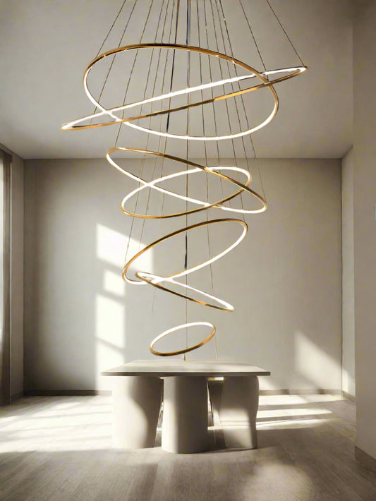 Tatva Lights Éclaire Cascade Gold Chandelier featuring cascading tiers of crystal-like elements and a polished gold finish, with integrated LED lighting—ideal for luxurious staircases, grand entryways, or upscale living spaces.