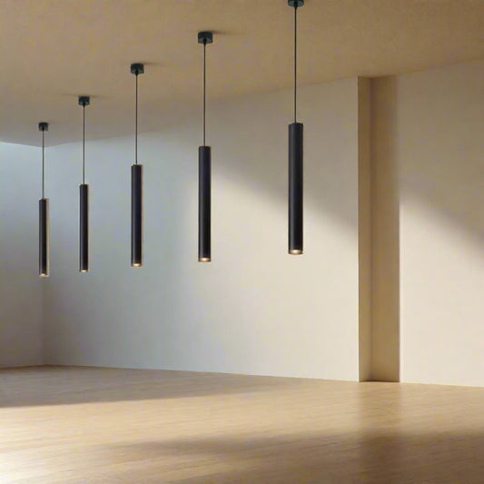 Tatva Lights Modern LED pendant lights with a cylindrical shape, hanging in a row over a kitchen counter with a white brick wall in the background.