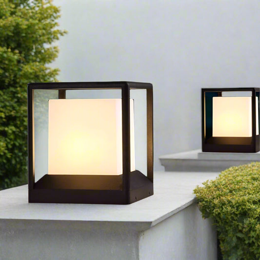 Tatva Lights modern outdoor cube pillar lights with frosted glass center and black metal frame, elegantly illuminating a garden pathway with warm ambient lights